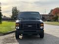A 2013 Ford E-350 Super Duty van with a black exterior is parked facing the camera showcasing its front grille headlights and windshield