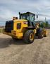 A 2016 CAT 938M wheel loader with a yellow exterior and large tires is positioned on a gravel surface