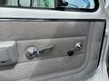 The interior door panel of a 1994 GMC Vandura 3500 featuring a textured grey fabric surface and chrome door handle and window controls