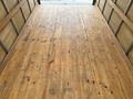 A 2024 Ford E-450 with a spacious wooden cargo area featuring a smooth floor and no visible items inside
