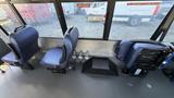 Interior view of a 2021 Ford Transit showing two blue seats and floor fittings for wheelchair accessibility