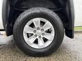 Close-up of a silver wheel and tire of a 2015 GMC Sierra 1500 showing the tread pattern on the tire and the wheel's five-spoke design
