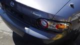 A gray 2007 Mazda Miata with a sleek design featuring round taillights and the "Roadster" badge on the rear trunk area