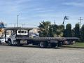 A 2022 Freightliner M2 106 flatbed truck loaded with palm trees on the back