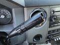 Close-up of a 2010 Ford F-450 steering column featuring the tow haul switch mounted on the left side of the steering wheel with dashboard controls visible in the background
