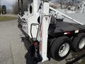 2008 Kenworth T370 with a flatbed and hydraulic lift system visible in the foreground showing its mechanical components and rear tire assembly