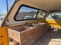 A 2013 Chevrolet Silverado 1500 with a wooden storage box in the truck bed and a raised camper shell over the cab area