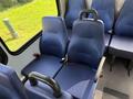 Two blue upholstered seats in the interior of a 2020 Chevrolet Express van with black armrests and seatbelts