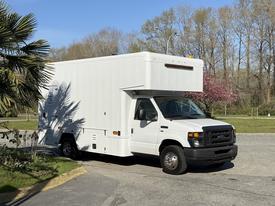 A white 2012 Ford Econoline E-450 box truck with a high roof and front headlights visible parked at an angle