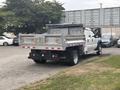 A 2014 Ford F-550 truck with a flatbed and a metal dump body parked in a lot with other vehicles in the background
