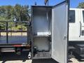 A 2011 International 4300 truck with an open compartment featuring shelves and a hose attachment inside the storage area