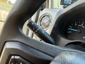 Close-up of a steering wheel with a turn signal lever and dashboard displaying speedometer and RPM gauge in a 2023 Ford E-450