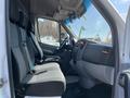 Interior of a 2010 Mercedes-Benz Sprinter featuring two front seats with gray upholstery and a driver's console with controls and storage compartments