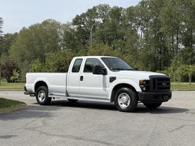 A white 2008 Ford F-250 Super Duty truck with a crew cab and long bed parked on a paved surface