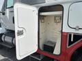 A 2012 International 7300 Workstar truck with an open storage compartment revealing an empty interior with a small black box at the bottom