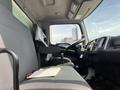Interior of a 2018 Hino 338 truck featuring a driver's seat with a gray fabric cover a steering wheel gear shift and various controls within the cabin
