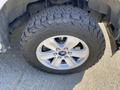 A close-up view of a 2018 Ford F-150 wheel featuring a metallic silver rim and an all-terrain tire with deep tread patterns