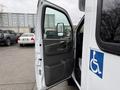 A white 2013 Chevrolet Express van with the driver's door open and a handicapped symbol on the door