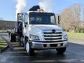 A 2015 Hino 358 truck with a flatbed and visible exhaust smoke coming from the rear