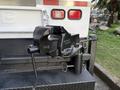 A 2010 Ford F-550 with a black trailer hitch coupler attached to the rear featuring a lever for securing and releasing the hitch