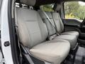 A gray interior of a 2019 Ford F-350 SD featuring two front seats with seat belts and a textured fabric design