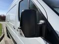 A close-up view of the side mirror and door of a white 2016 Mercedes-Benz Sprinter van