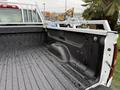 A 2015 GMC Sierra 1500 truck bed with a diamond plate metal rack and a textured black liner showing water droplets