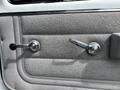 Interior door handle and window crank of a 1994 GMC Vandura 3500 with a textured light gray panel and chrome accents