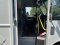 The interior of a 2018 Ford Econoline showing the driver's seat a steering wheel and a yellow handrail leading into the cab