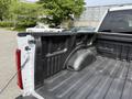 A 2021 Ford F-150 truck bed showing a textured black liner with a wheel well and cargo tie-downs visible in the corners