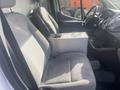 Interior of a 2017 Ford Transit showing two gray front seats and a metallic storage compartment between them