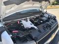 A 2020 Chevrolet Express with its hood open displaying the engine compartment highlighting various components such as the battery and coolant reservoir