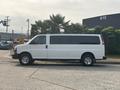 2021 Chevrolet Express van in white with dark tinted windows parked on a driveway with chrome wheels
