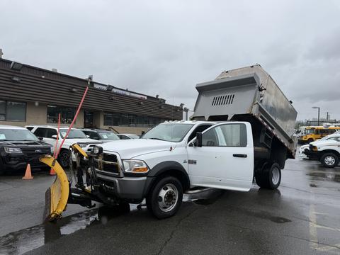 A 2011 Dodge Ram 5500 dump truck with a plow attached in the front and the dump bed raised