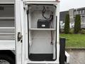 A 2024 RAM 5500 service truck with an open compartment featuring shelves and a battery mounted inside