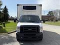 A white 2023 Ford E-450 box truck with a large front grille and black bumper parked in a lot