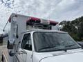 A 1994 GMC Vandura 3500 with a white exterior and a distinct roof-mounted light bar designed for emergency or utility use
