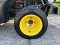 A yellow wheel of a 2021 John Deere 1575 featuring a black tire with a thick tread and five bolt holes in the center