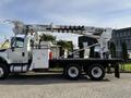 A white 2011 International 7500 truck with a hydraulic boom and bucket attached for utility work