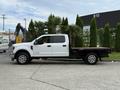 A white 2019 Ford F-350 SD with a flatbed is parked on a concrete surface showcasing its spacious cabin and large tires