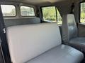 The interior cabin of a 2006 Sterling Acterra featuring a gray bench seat and a single gray driver seat with a mesh divider separating the front and back seats