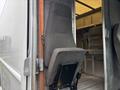 A gray seat from a 2012 Ford E-450 Super Duty van is partially folded up and mounted inside the vehicle's entryway