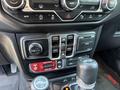 A 2021 Jeep Wrangler's dashboard with controls for climate, media, and four-wheel drive settings along with a gear shift lever and power outlet