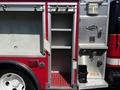 A red and silver fire truck with open storage compartments and equipment mounted on the side