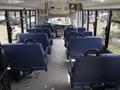 Interior view of a 2020 Chevrolet Express with several rows of blue upholstered seats and a driver's area at the front