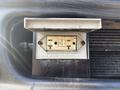A power outlet with two vertical slots and a grounding slot mounted on a metal surface of a 2008 International 4400 vehicle