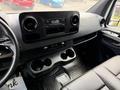 Interior view of a 2022 Mercedes-Benz Sprinter showing the dashboard with a radio display air vents and cup holders