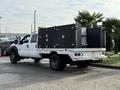 A 2015 Ford F-550 with a flatbed and black storage compartments on the back