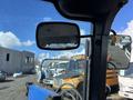 A 2010 New Holland T4050 tractor with a blue front loader visible from the driver's perspective showing the rearview mirror and part of the cab