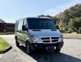 A silver 2007 Dodge Sprinter van viewed from the front angle with a high roof and large windows, showcasing its boxy shape and distinctive grille